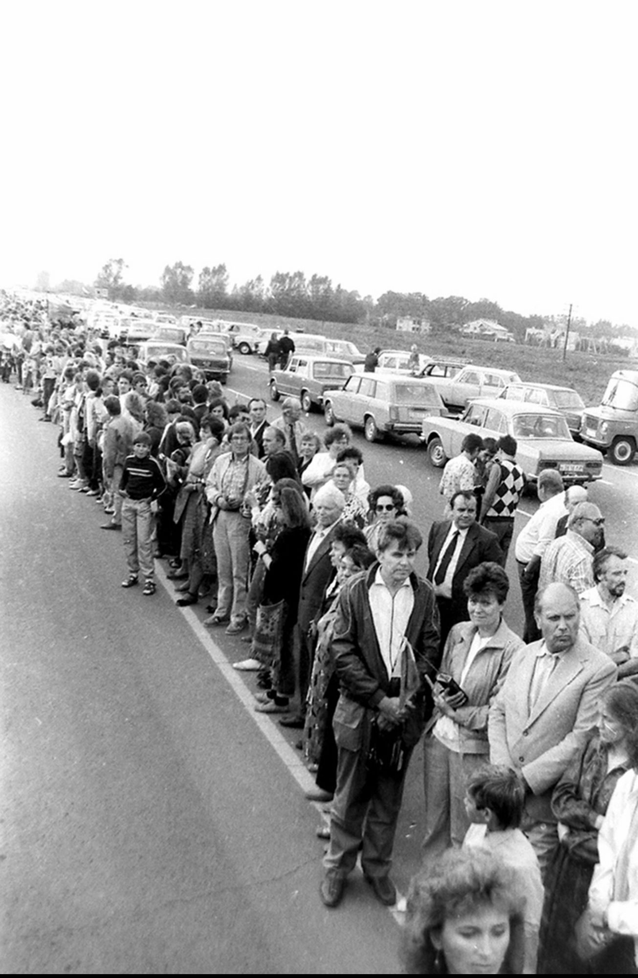 Uma linha ininterrupta de pessoas de mãos dadas ao longo de uma estrada durante a The Baltic Way, a 23 de agosto de 1989